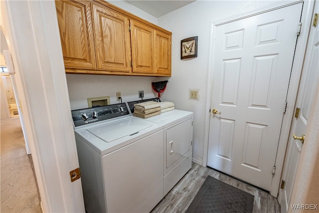 washroom with washing machine and clothes dryer, cabinet space, and light wood-style floors