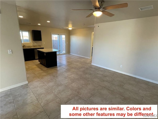 kitchen featuring visible vents, open floor plan, dark cabinets, a center island, and light countertops