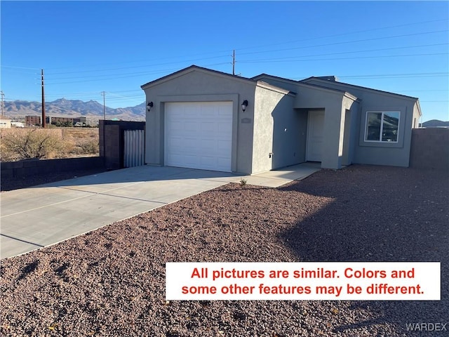 view of front of property featuring a mountain view, a garage, fence, driveway, and stucco siding