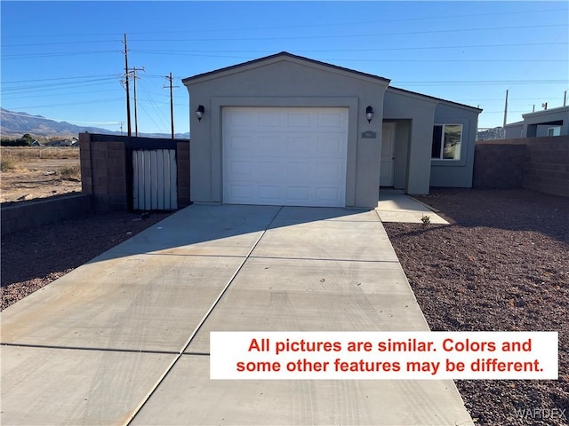 view of front of home featuring a mountain view, a garage, fence, driveway, and stucco siding