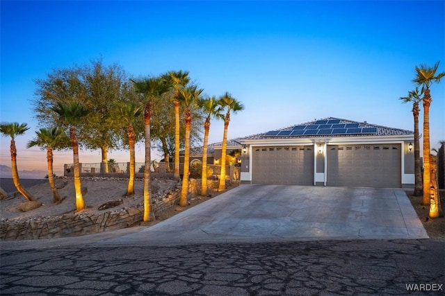 view of front of house with a garage, stucco siding, solar panels, and concrete driveway