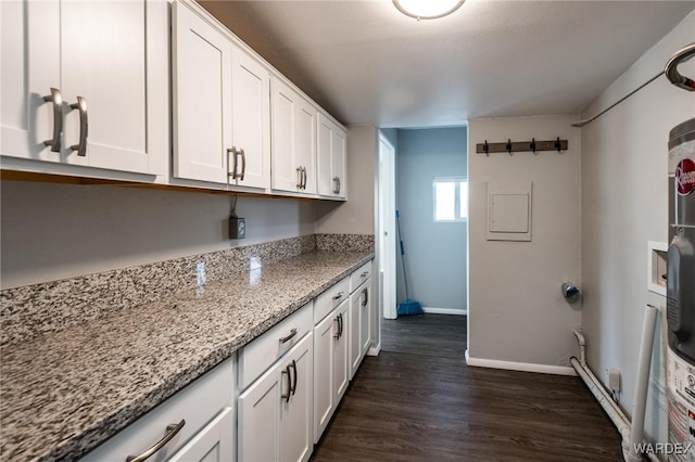 kitchen with dark wood-style floors, baseboards, white cabinetry, and light stone counters