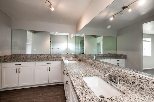 full bath featuring double vanity, a sink, track lighting, and wood finished floors