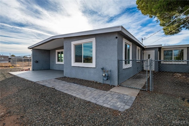 view of side of home featuring fence, a patio, and stucco siding