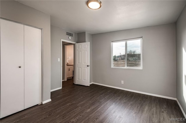 unfurnished bedroom featuring baseboards, visible vents, dark wood finished floors, and a closet