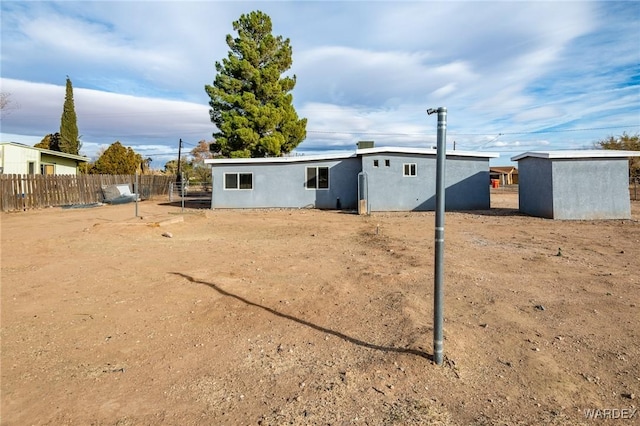 back of property featuring a shed, fence, and stucco siding