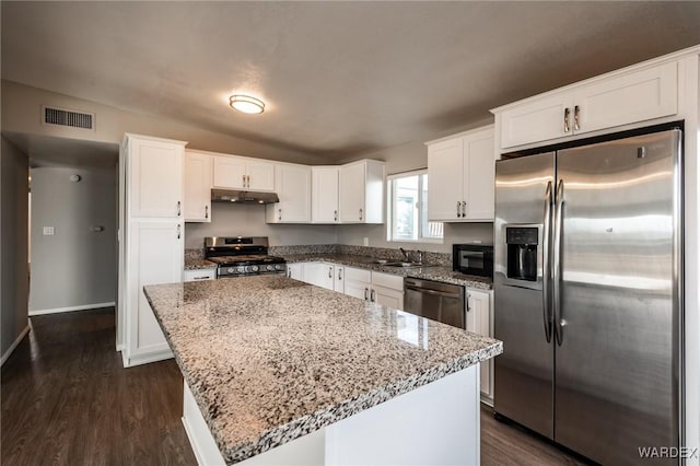 kitchen with under cabinet range hood, visible vents, white cabinets, appliances with stainless steel finishes, and a center island