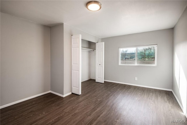 unfurnished bedroom featuring dark wood-style floors, baseboards, and a closet