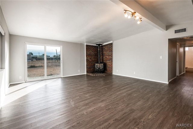 unfurnished living room with vaulted ceiling with beams, visible vents, baseboards, dark wood finished floors, and a wood stove