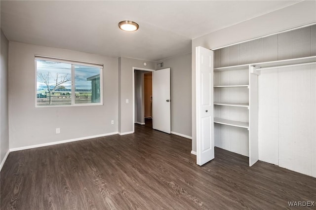 unfurnished bedroom featuring dark wood-style floors, baseboards, visible vents, and a closet