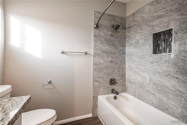 full bath featuring baseboards, toilet, shower / bathtub combination, wood finished floors, and vanity