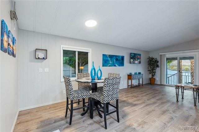 dining area with lofted ceiling, light wood-style flooring, and baseboards