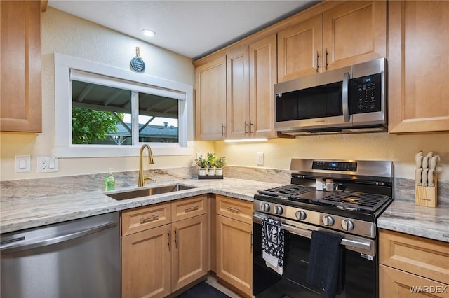 kitchen featuring stainless steel appliances, light stone counters, and a sink