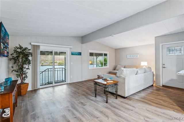 living area featuring vaulted ceiling with beams and light wood-type flooring