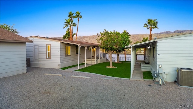 rear view of house with central AC, a yard, fence, and a mountain view