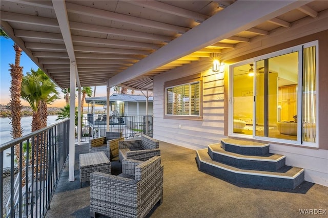 patio terrace at dusk featuring entry steps, a water view, and a balcony