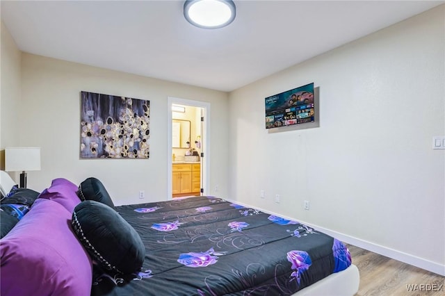 bedroom with connected bathroom, baseboards, and wood finished floors