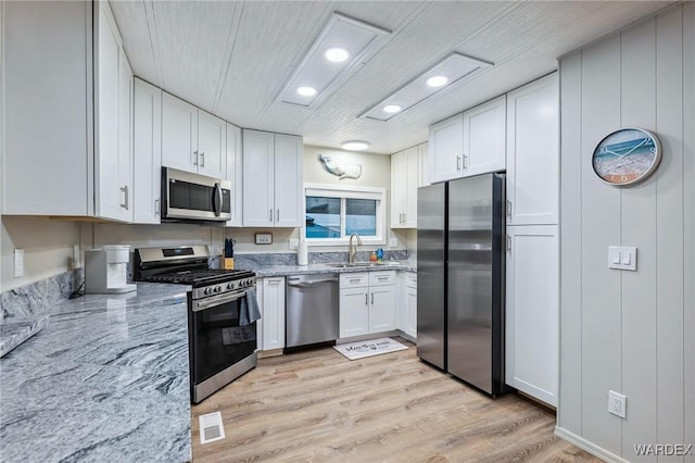 kitchen featuring stainless steel appliances, white cabinetry, and a sink