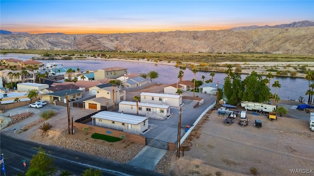 aerial view at dusk featuring a water and mountain view and a residential view