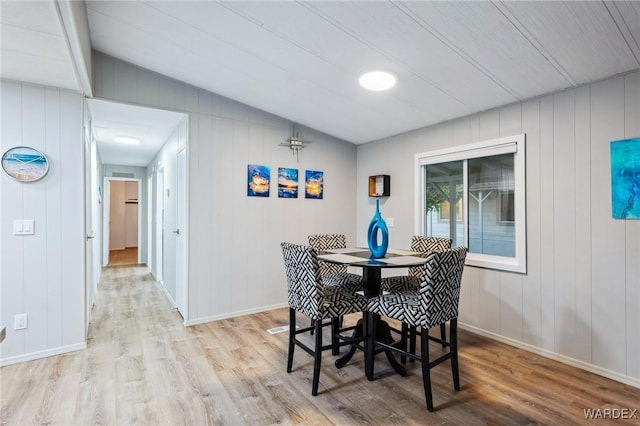 dining area with lofted ceiling, light wood-style floors, and baseboards