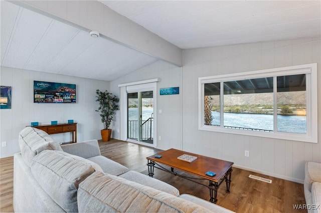 living area with visible vents, vaulted ceiling with beams, and wood finished floors