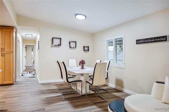 dining area with dark wood-type flooring and baseboards