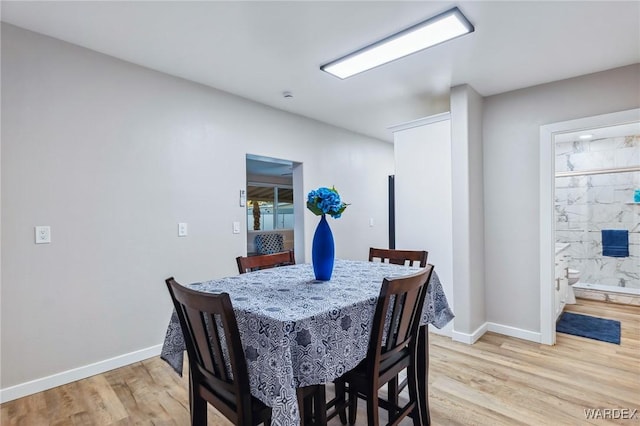 dining space featuring light wood-style flooring and baseboards