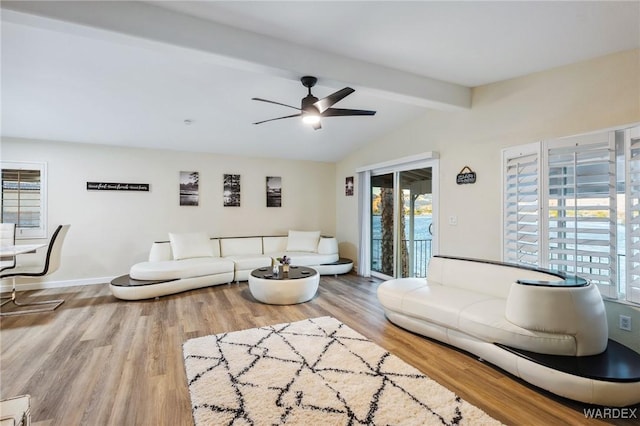 living area with ceiling fan, lofted ceiling with beams, baseboards, and wood finished floors