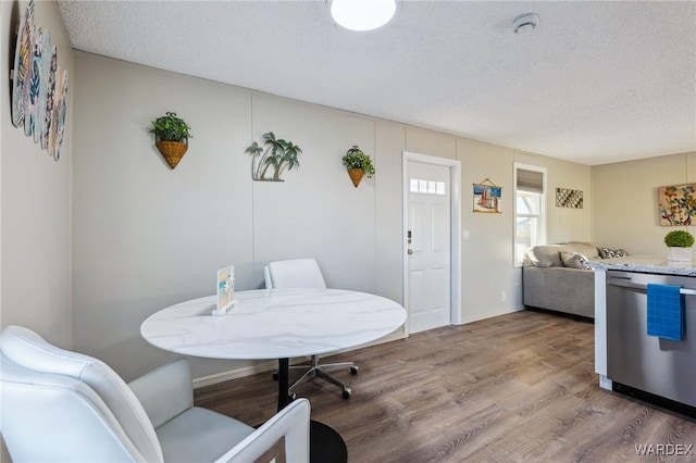 dining space with a textured ceiling, baseboards, and wood finished floors