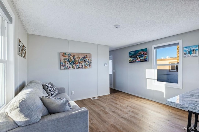 living area featuring a textured ceiling, wood finished floors, and visible vents