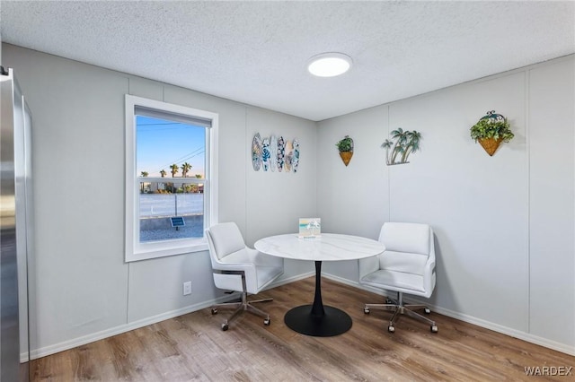 dining room with breakfast area, a textured ceiling, baseboards, and wood finished floors