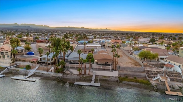 aerial view at dusk with a water view and a residential view