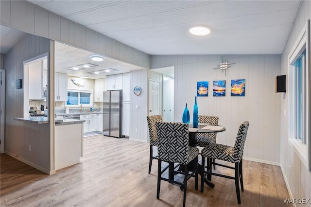 dining space featuring light wood finished floors and baseboards