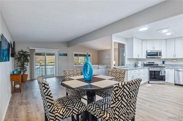 dining space featuring vaulted ceiling and light wood finished floors