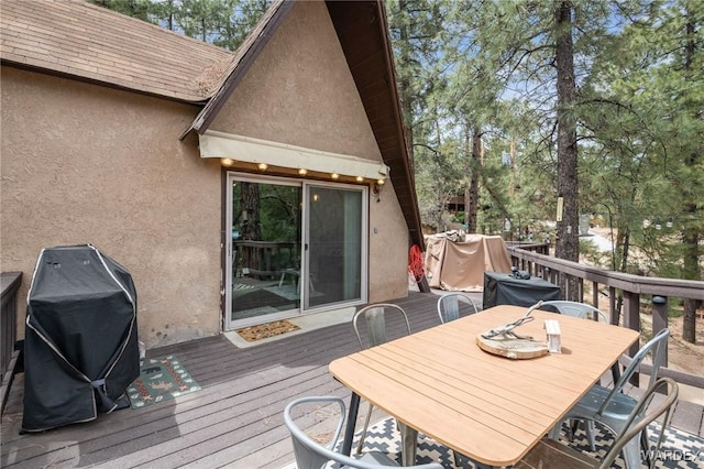 wooden terrace with outdoor dining space and a grill
