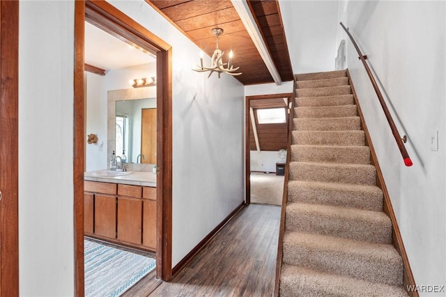 stairway featuring an inviting chandelier, baseboards, beamed ceiling, and wood finished floors