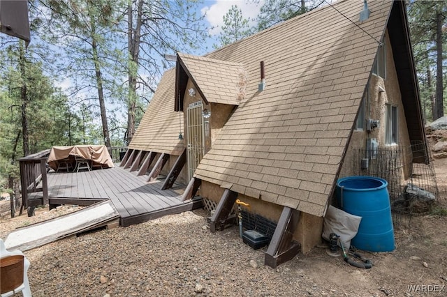 view of side of property featuring a shingled roof and a deck