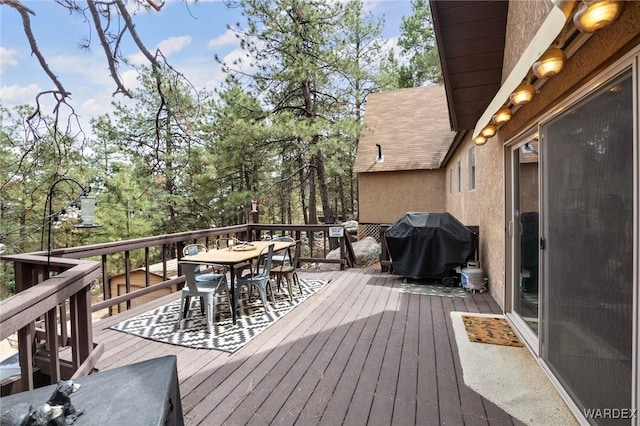wooden terrace featuring area for grilling and outdoor dining area