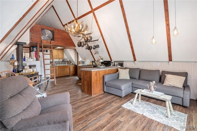 living area featuring an inviting chandelier, a wood stove, beam ceiling, wood finished floors, and high vaulted ceiling