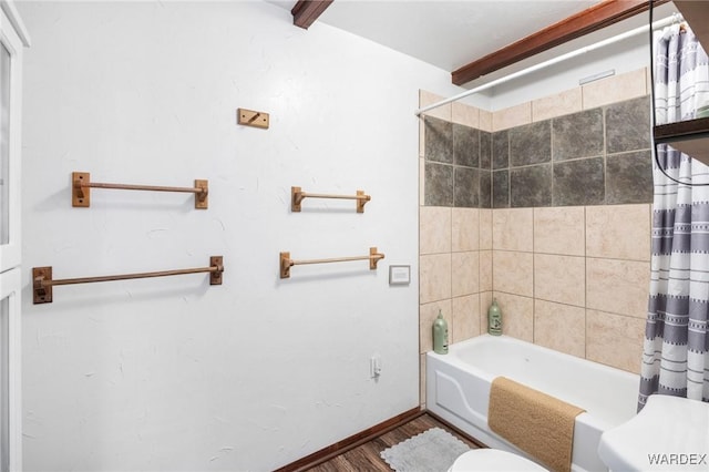 bathroom with baseboards, toilet, wood finished floors, and shower / tub combo