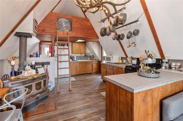 kitchen featuring brown cabinetry, white microwave, dark wood-style floors, high vaulted ceiling, and black range with gas cooktop
