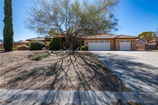 view of front of house featuring driveway, a garage, a tile roof, fence, and stucco siding