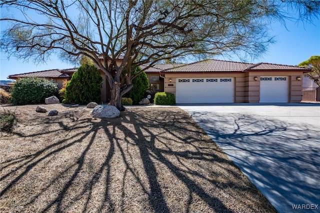 view of front of property with a tile roof, driveway, an attached garage, and stucco siding