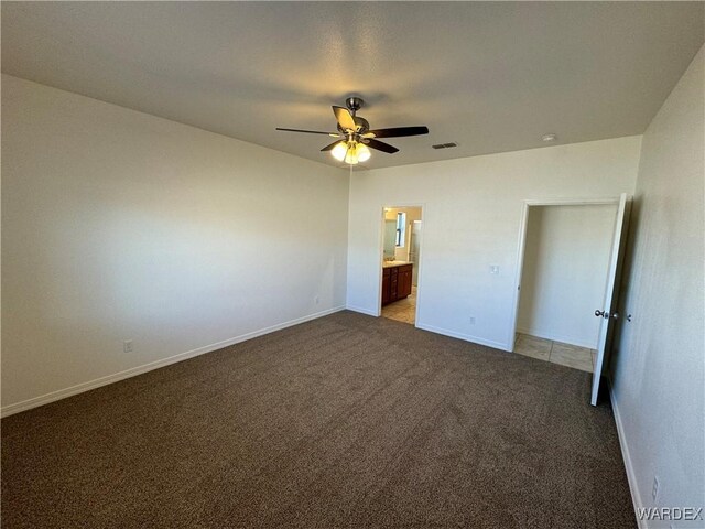 unfurnished bedroom with ensuite bathroom, ceiling fan, carpet flooring, visible vents, and baseboards