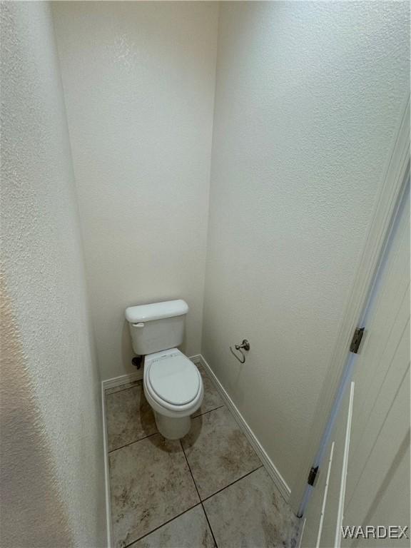 bathroom featuring toilet, baseboards, and tile patterned floors