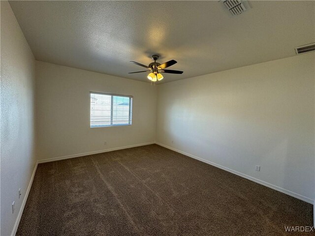 spare room with baseboards, visible vents, dark carpet, and a ceiling fan