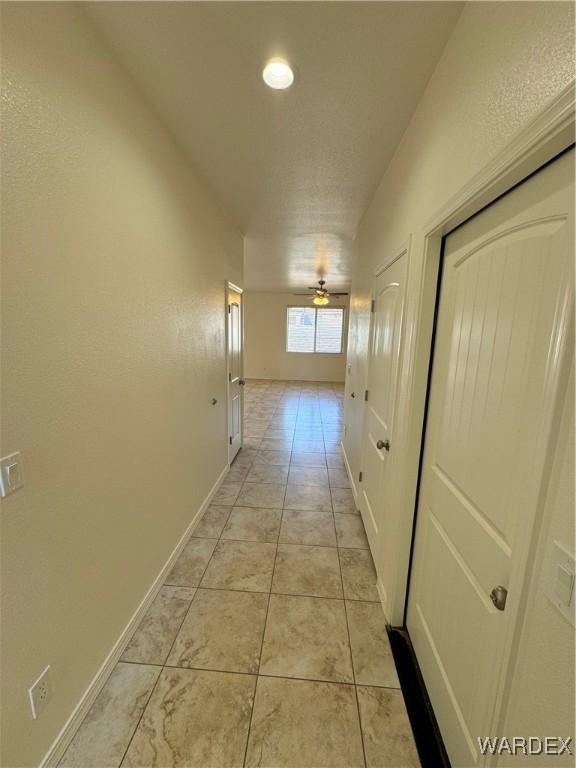 corridor featuring light tile patterned floors and baseboards