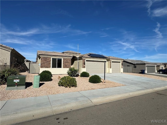 view of front of property with solar panels, concrete driveway, a garage, a residential view, and stone siding