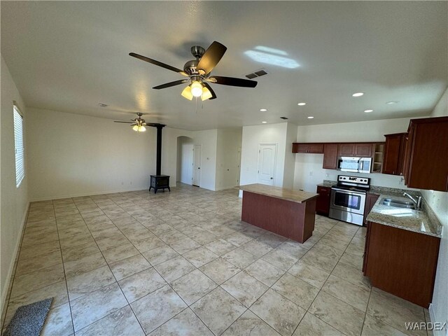 kitchen with light stone counters, stainless steel appliances, visible vents, open floor plan, and a sink