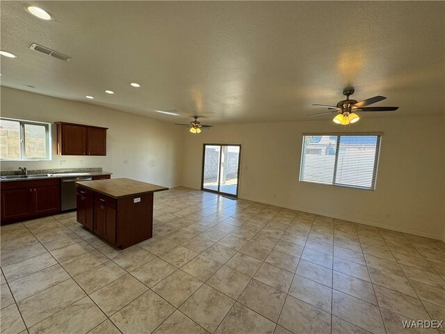 kitchen featuring a sink, a kitchen island, visible vents, open floor plan, and dishwasher